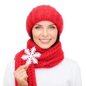 happiness, winter holidays, christmas and people concept - smiling young woman in red hat, scarf and mittens holding snowflake decoration over white background