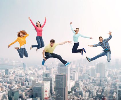 happiness, freedom, friendship, movement and people concept - group of smiling teenagers jumping in air over city background