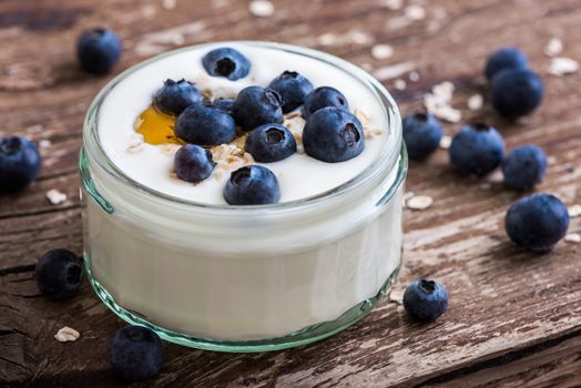 Serving of Yogurt with Whole Fresh Blueberries and Oatmeal on Old Rustic Wooden Table. Closeup Detail.