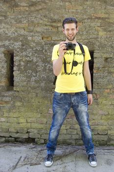 Young smiled man taking a photo in yellow t-shirt