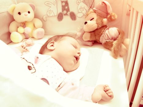 Newborn baby sleeping with toys vintage photo