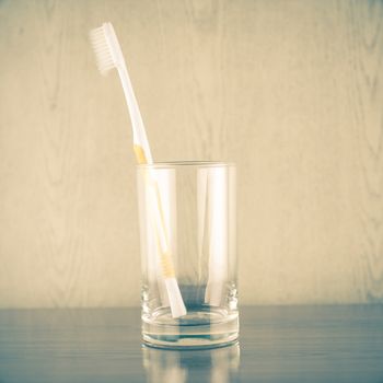 toothbrush in glass on wood background vintage style