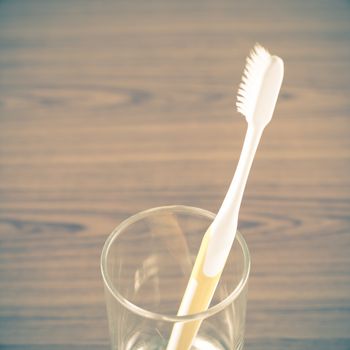 toothbrush in glass on wood background vintage style