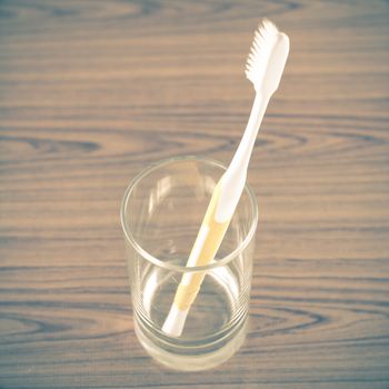 toothbrush in glass on wood background vintage style