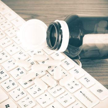 pills on keyboard computer on wooden background concept technology addiction vintage style