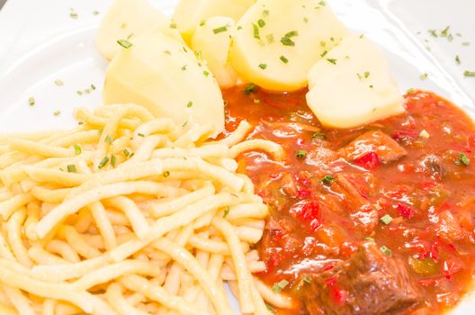 Beef stew on a plate with potatoes and pasta. Goulash is a stew which comes from Hungary.