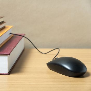 book and computer mouse on wood background