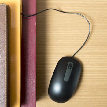 book and computer mouse on wood background