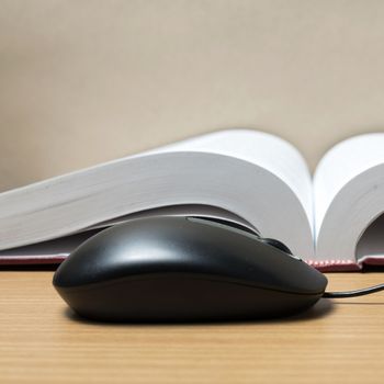 book and computer mouse on wood background