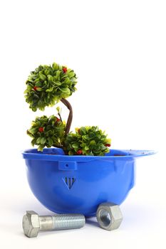 Green plant in blue helmet on white - environmental friendly industry concept