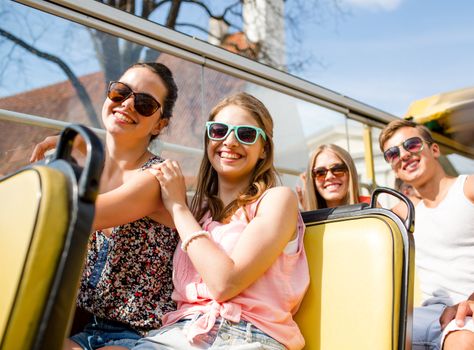 friendship, travel, vacation, summer and people concept - group of smiling friends traveling by tour bus