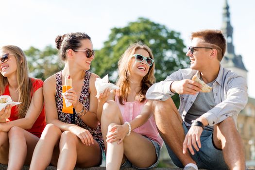 friendship, leisure, summer and people concept - group of smiling friends in sunglasses sitting with food on city square