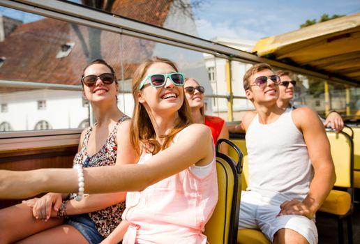 friendship, travel, vacation, summer and people concept - group of smiling friends traveling by tour bus