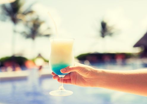 vacation, beverage and travel concept - close-up of female hand holding glass with cocktail