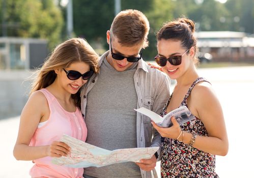 travel, tourism, vacation, summer and people concept - smiling friends with map and city guide outdoors