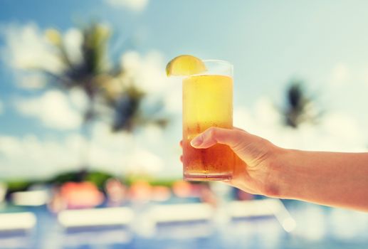 vacation, beverage and travel concept - close-up of female hand holding glass with cocktail