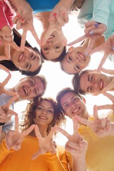 friendship, youth, gesture and people - group of smiling teenagers in circle showing victory sign