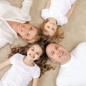 family, children and home concept - smiling family with and two little girls lying in circle on floor at home