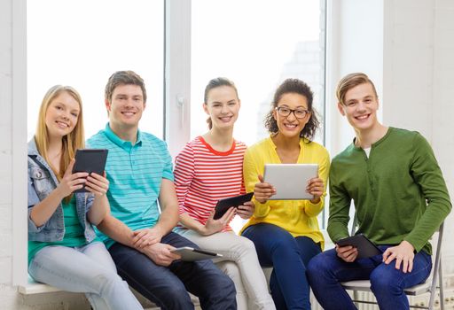 education and technology concept - smiling students with tablet pc computer at school