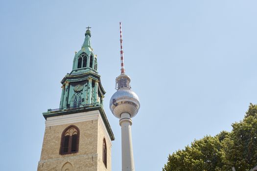 BERLIN, GERMANY - JULY 07: Low angle shot of TV tower in Alexanderplatz, with Saint Mary's Church tower in the foreground. July 07, 2015 in Berlin.