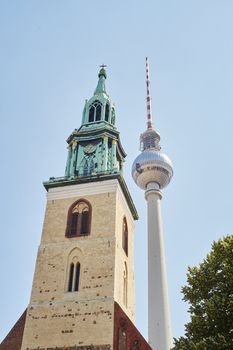 BERLIN, GERMANY - JULY 07: Low angle shot of TV tower in Alexanderplatz, with Saint Mary's Church tower in the foreground. July 07, 2015 in Berlin.