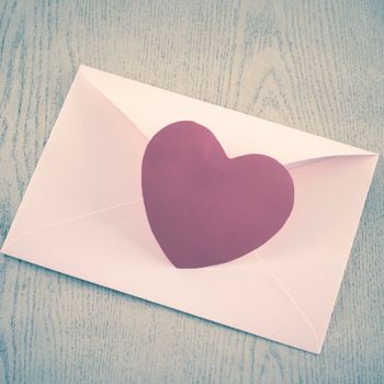 red heart with pink envelope on wooden background vintage style