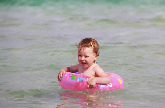 Little girl with rubber ring in the sea