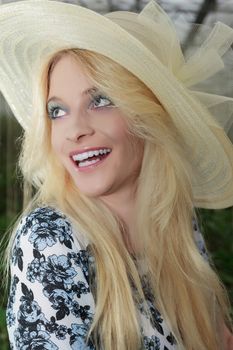 Close up Stylish Pretty Blond Woman Wearing Elegant Straw Hat and Looking Into the Distance with Happy Facial Expression.