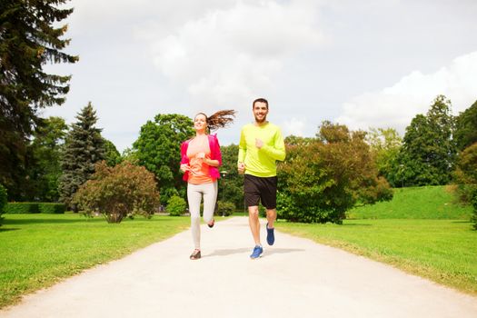 fitness, sport, friendship and lifestyle concept - smiling couple running outdoors