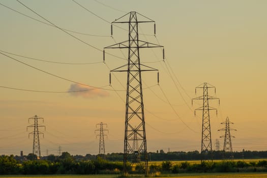 group of electricity pylons in a field at early evening