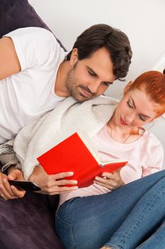 Close up Sweet Young Couple Resting at the Couch in the Living Area While Reading a Book Together Seriously.