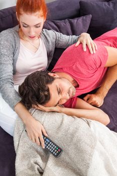 Young Couple Relaxing on the Couch In the Living Room, with Pensive Facial Expressions, While Boyfriend is Lying on the Lap of her Girlfriend.