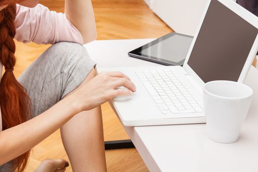 Pretty Young Woman Using her Laptop Computer In the Living Room with Feet on the Table and Showing Serious Face.