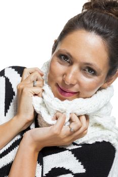 Attractive elegant woman in winter fashion snuggling down into her white scarf and black and white jumper to ward off the cold winter weather, on white