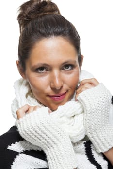 Attractive elegant woman in winter fashion snuggling down into her white scarf and black and white jumper to ward off the cold winter weather, on white