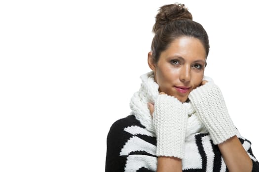 Attractive elegant woman in winter fashion snuggling down into her white scarf and black and white jumper to ward off the cold winter weather, on white