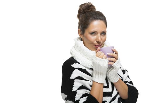 Cold attractive stylish woman in an elegant black and white winter outfit clasping a mug of hot coffee in her hands while savoring the aroma with a look of anticipation