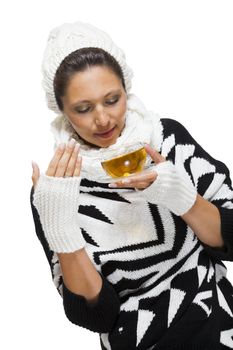 Elegant woman in a stylish black and white winter outfit with matching white mitts, scarf and knitted hat drinking a cup of hot tea, isolated on white