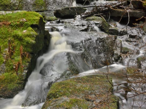 a small waterfall with rocks covered with moss