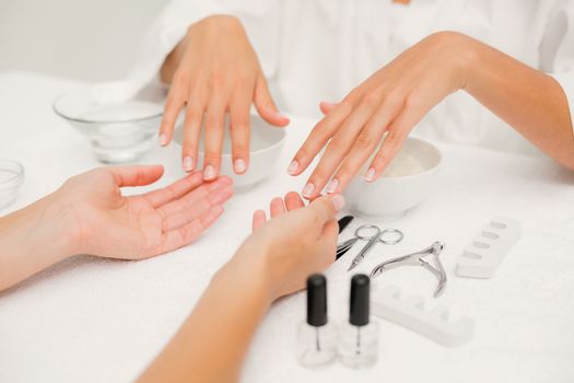 Close up of beautician filing female clients nails at spa beauty salon