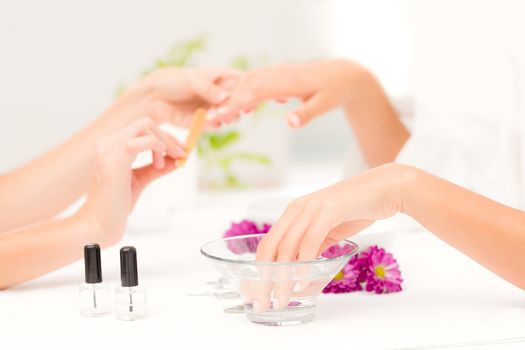 Close up of beautician filing female clients nails at spa beauty salon