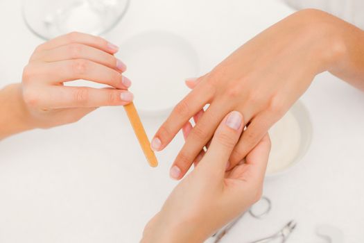 Close up of beautician filing female clients nails at spa beauty salon