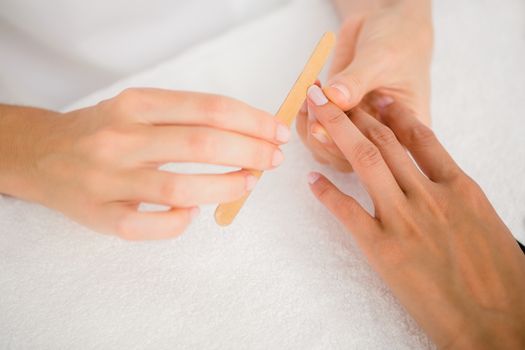 Close up of beautician filing female clients nails at spa beauty salon