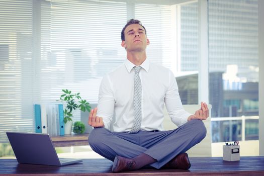 Zen businessman doing yoga meditation on the desk