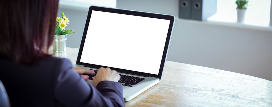 Businesswoman working at her desk on laptop in her office