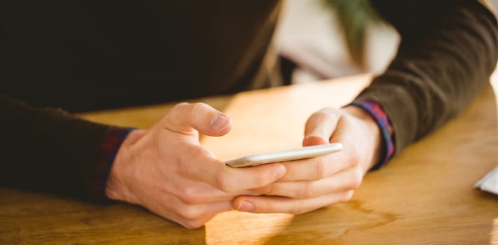 Hipster businessman sending a text in his office