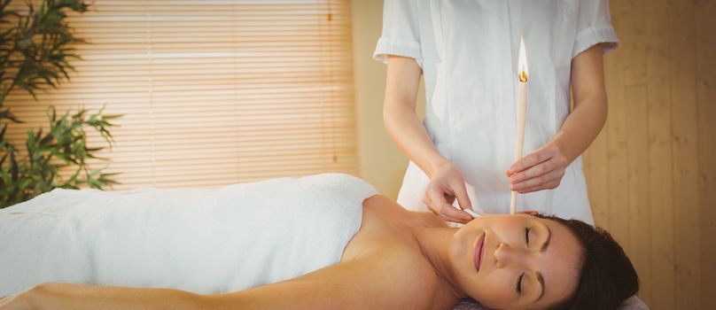 Young woman getting an ear candling treatment in therapy room