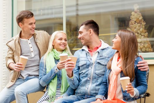 friendship, travel, drink and vacation concept - group of smiling friends with take away coffee