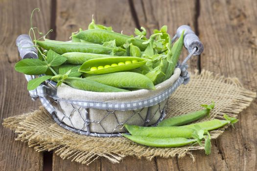 basket full of green peas on wooden background