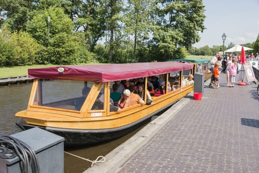 GIETHOORN, NETHERLANDS - JULY 18, 2015: Unknown tourists on boating trip in a canal in Giethoorn on july 18 2015. The beautiful houses and gardening city is know as "Venice of the North"